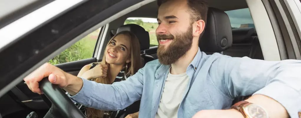 Casal sorrindo dentro do carro