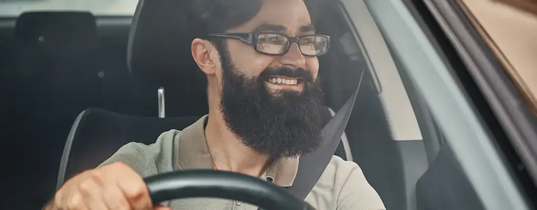 Motorista de aplicativo dentro de carro alugado sorrindo