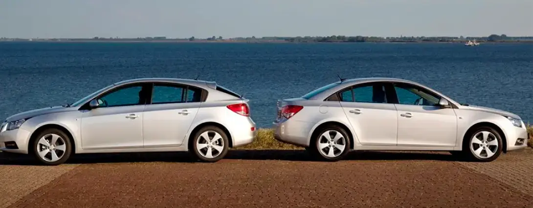 Dois veículos sedan em frente a uma paisagem