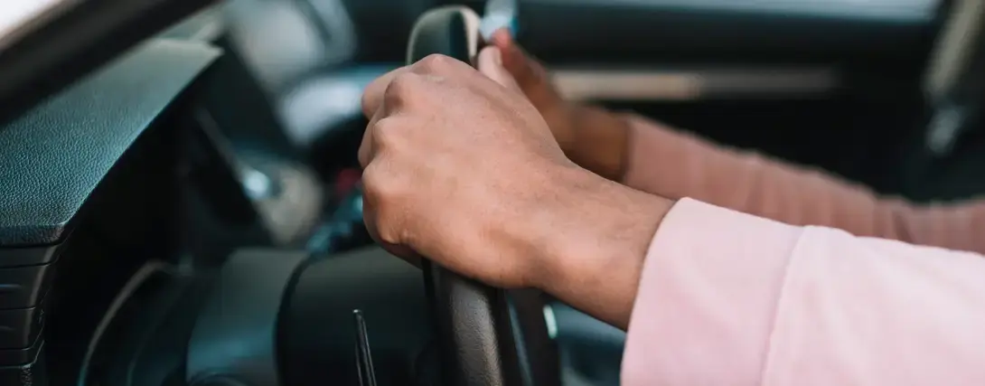 Close em mãos segurando o volante de um carro