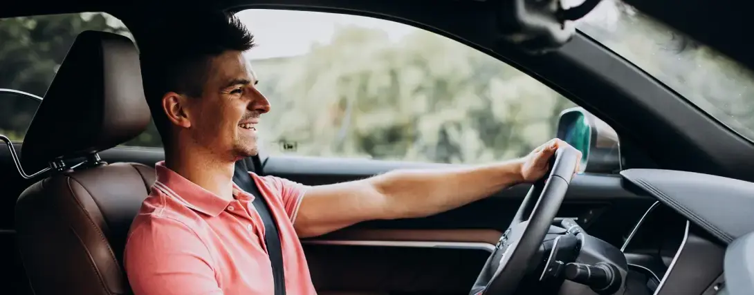 Homem sorrindo dentro do carro com uma mão no volante