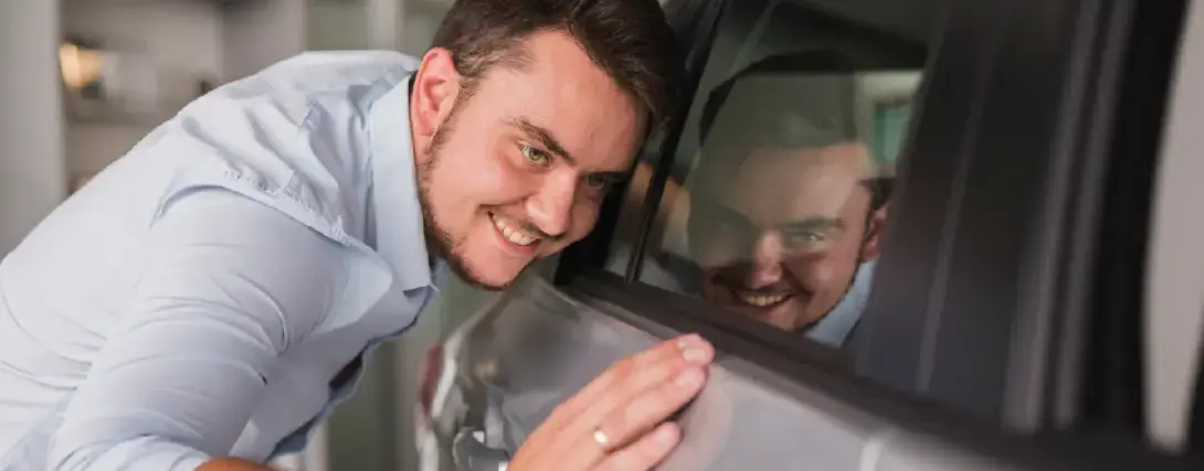 Homem sorrindo analisando detalhes do veículo prata