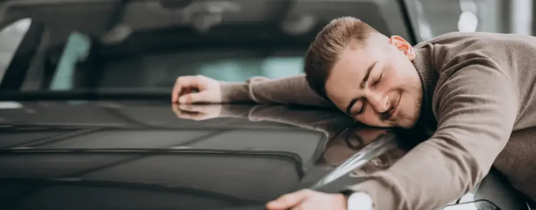 Homem feliz abraçando seu carro